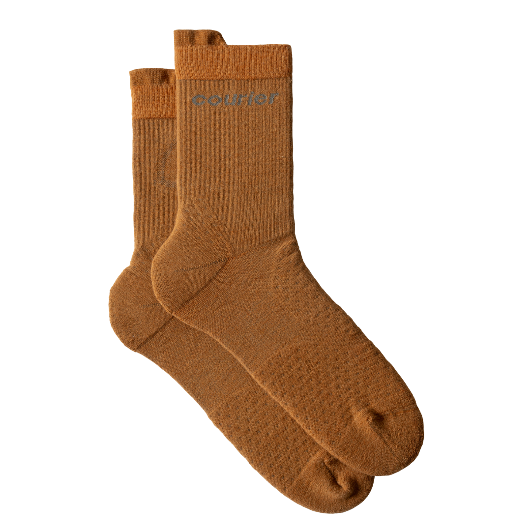 A pair of mid-calf knit socks in a warm camel brown color, featuring a subtle textured pattern and the brand name 'soldier' printed in gray on the ribbed cuff, set against a plain white background.